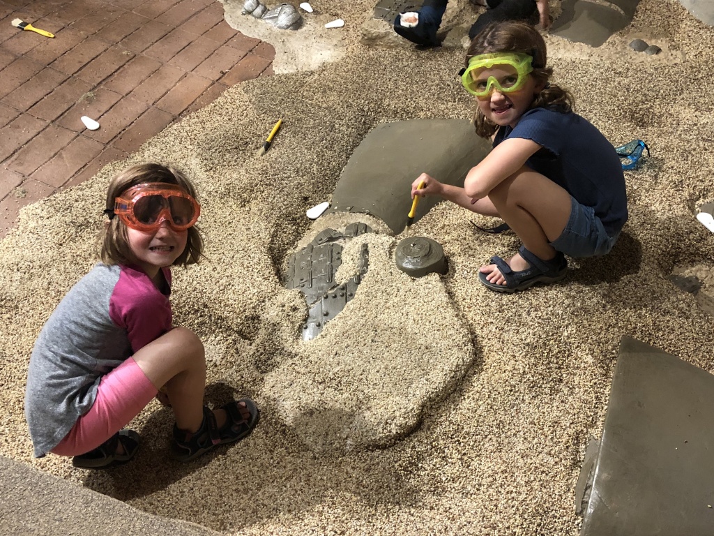 Children unearthing dinosaur artifacts in the sand